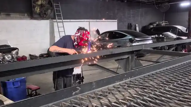 Garazh welder repairing a car hauler trailer frame in the bay