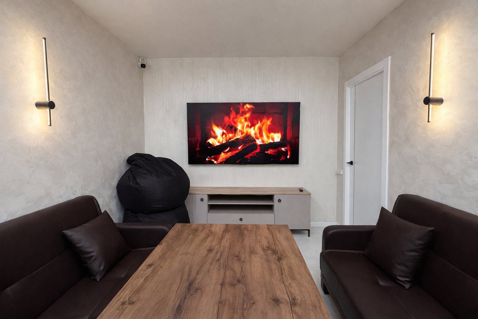 Интерьер Quest Lounge с камином на экране, диванами и деревянным столом